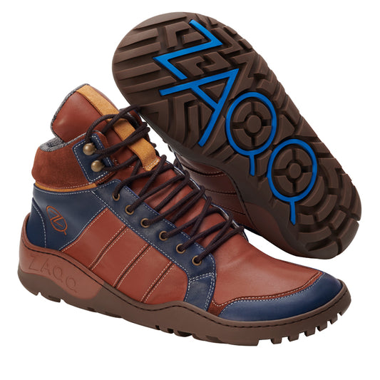 Der Q2 Cognac Waterproof von ZAQQ ist ein modischer High-Top-Lederstiefel, der eine auffällige Mischung aus Braun-, Blau- und Hellbrauntönen aufweist. Er verfügt über die ikonische ZAQQ TERRA-Sohle, ist aus hochwertigem Nappaleder gefertigt und verfügt über ein robustes Schnürdesign, das durch ein markantes blaues Branding auf der Sohle und auffällige Nähte ergänzt wird.