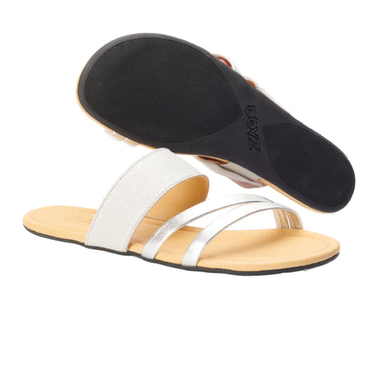 Wir präsentieren die QATE Silver White von ZAQQ, ein Paar flache Sandalen, die sich durch ein schlichtes und doch elegantes Design auszeichnen. Eine Sandale ist so positioniert, dass ihre schwarze rutschfeste Sohle sichtbar ist, während die andere über zwei metallisch-silberne Riemen aus hochwertigem Nappaleder und ein hellbeiges Fußbett verfügt.