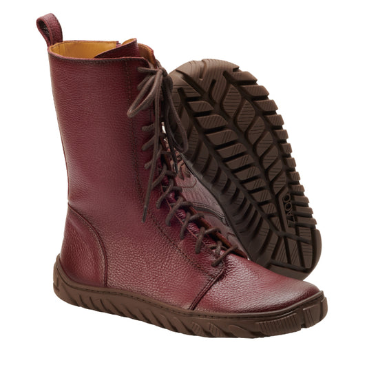 Die ZAQQ DOQS Bordeaux Stiefel aus luxuriösem Premium Nappaleder in einem satten Burgunderton strahlen Eleganz aus. Mit ihrem kniehohen Design, den braunen Sohlen und Schnürsenkeln steht ein Stiefel aufrecht, während der andere sich neigt, um die ULTRAGRIP Sohle für optimale Traktion freizugeben.