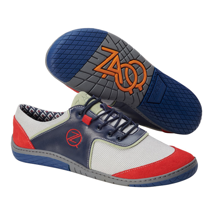 Entdecke den modischen ZAQQ Barfuß-Sneaker aus der QOLETTE Blue Linie mit Einsätzen in Rot, Marineblau und Weiß. Die Sohle ist mit einem orangefarbenen Logo-Design verziert, während das Innere ein gemustertes Futter aufweist. Diese Schuhe versprechen sowohl Komfort als auch Stil, komplett mit einem markanten runden Logo an der Seite.