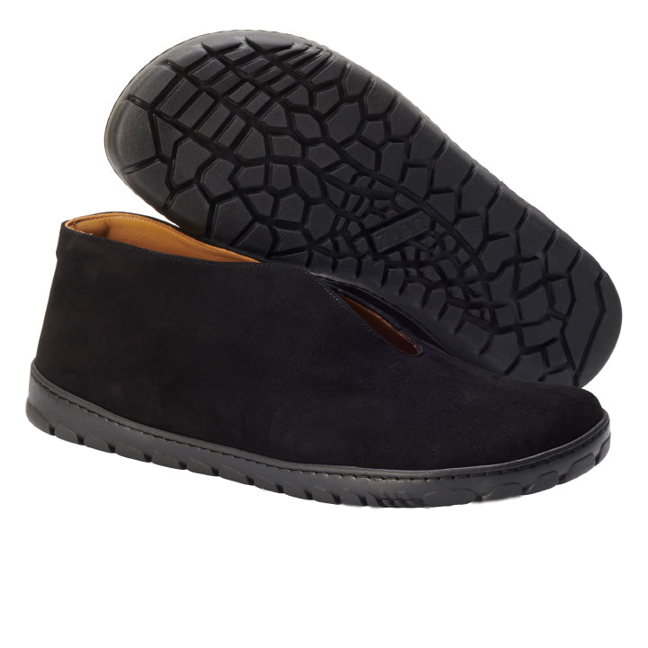 Die Slipper ZAQQ TSEQA Black bestechen durch ihr schlichtes, glattes Design aus Premium Veloursleder. Ein Schuh ist aufrecht abgebildet, während der andere seine strukturierte OUTDOOR-Sohle zeigt, die mit einer dezent erhöhten Rückseite eine Mischung aus Stil und Halt bietet.