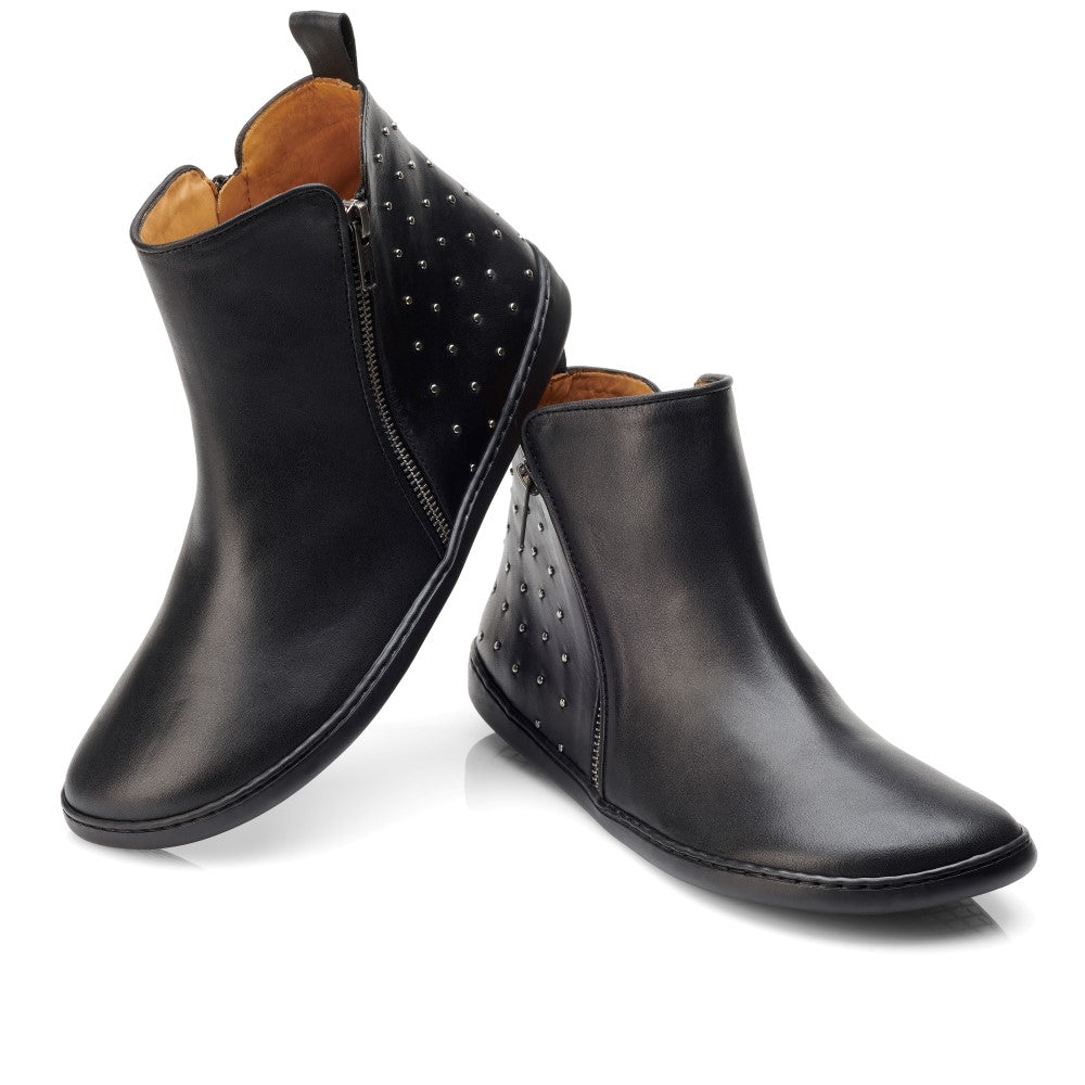 Wir präsentieren den QLARE Black von ZAQQ: Ein Paar elegante schwarze Stiefeletten mit seitlichen Reißverschlüssen und kantiger Nietenverzierung an der Ferse, elegant präsentiert vor einem weißen Hintergrund. Diese Stiefel verfügen über ein glattes Lederfinish und eine rutschhemmende Sohle für verbesserte Stabilität.