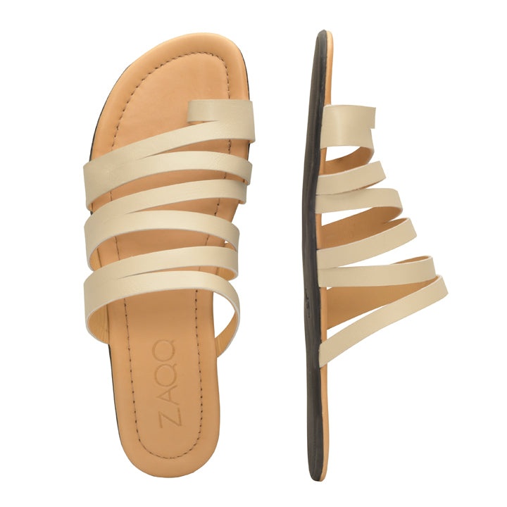 Wir präsentieren die FLAQE Beige Sandalen von ZAQQ: Diese Riemchensandalen sind aus hochwertigem Nappaleder gefertigt und verfügen über eine flache, flexible Sohle. Die mehreren Riemen kreuzen elegant den Fuß. Das Bild zeigt eine Sandale von oben und die andere von der Seite, alles vor einem schlichten weißen Hintergrund.