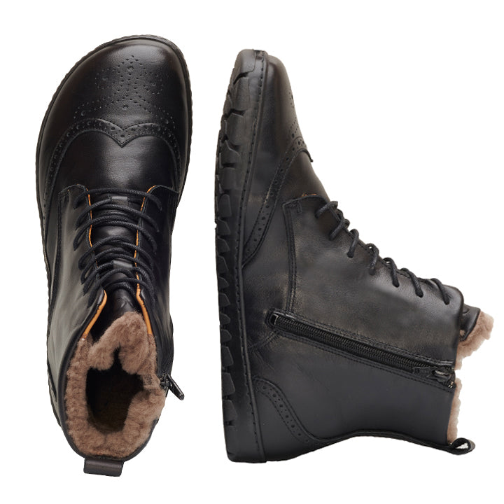 Die QUINTIC Winter Brogue Black Stiefel von ZAQQ sind vor einem weißen Hintergrund abgebildet. Ein Stiefel ist von oben zu sehen und zeigt sein Schnürdesign und sein braunes Innenfutter, während der andere sein Seitenprofil mit Reißverschluss und strukturierter Sohle zeigt und so die Eleganz eines Brogue-Stils einfängt.