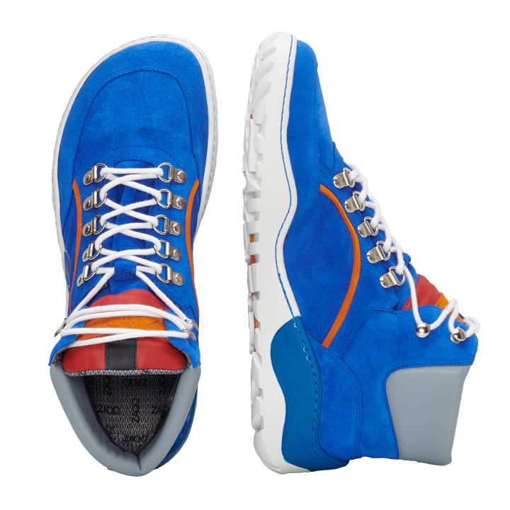 Der TERRAQ Azure Waterproof von ZAQQ ist ein Paar leuchtend blaue Wildleder-Wanderstiefel mit weißen Schnürsenkeln und Metallösen. Diese Outdoor-Schuhe haben orangefarbene Akzente und eine robuste weiße Sohle mit grauem Absatz. Ein Stiefel steht aufrecht, während der andere auf der Seite liegt.