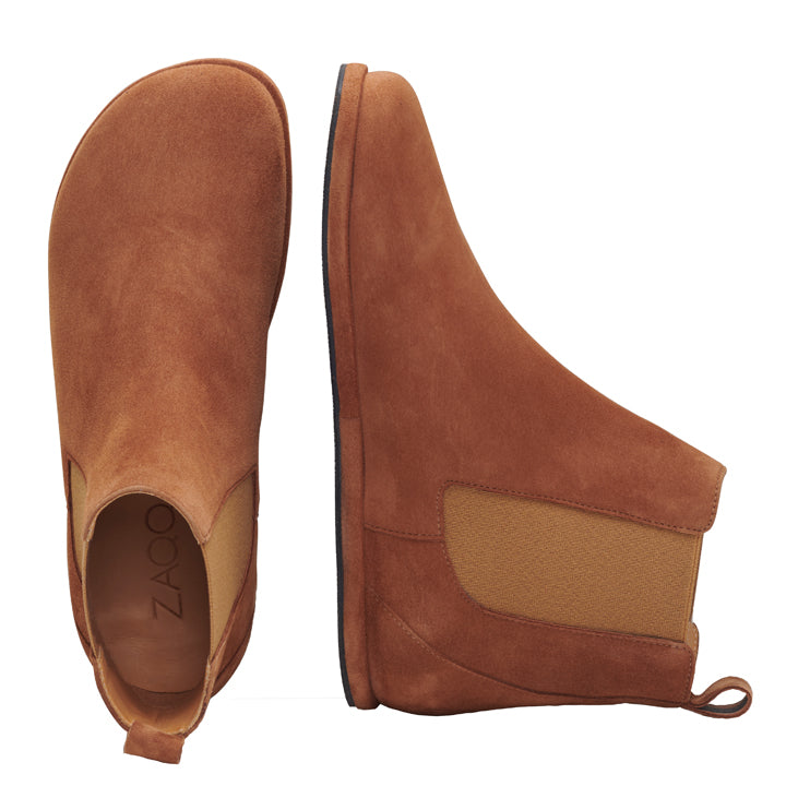 Das Paar EQUITY Cognac von ZAQQ ist ein Chelsea-Boot aus braunem Veloursleder mit elastischen Seiteneinsätzen und Laschen. Ein Boot ist von oben zu sehen, während der andere von der Seite gezeigt wird, um die dicke Sohle und das elegante Design hervorzuheben.