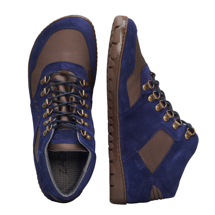 Wir präsentieren die wasserdichten HIQE Mid Navy-Stiefel von ZAQQ. Diese High-Top-Stiefel sind von der Seite und von oben zu sehen und zeigen eine stilvolle Kombination aus blauem Wildleder und braunem Stoff. Sie verfügen über schwarze Schnürsenkel, dunkelbraune Sohlen, Metallösen und sichtbare Nähte und bieten sowohl Stil als auch Haltbarkeit für jedes Outdoor-Abenteuer.