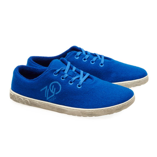 Die LIQE Azur Sneaker von ZAQQ aus Merinowolle haben hellgraue Sohlen und blaue Schnürsenkel. Jeder Schuh zeigt stolz ein kreisförmiges Logo mit der Nummer 700 vor einem schlichten weißen Hintergrund und verbindet bei jedem Schritt nahtlos Komfort und Stil.