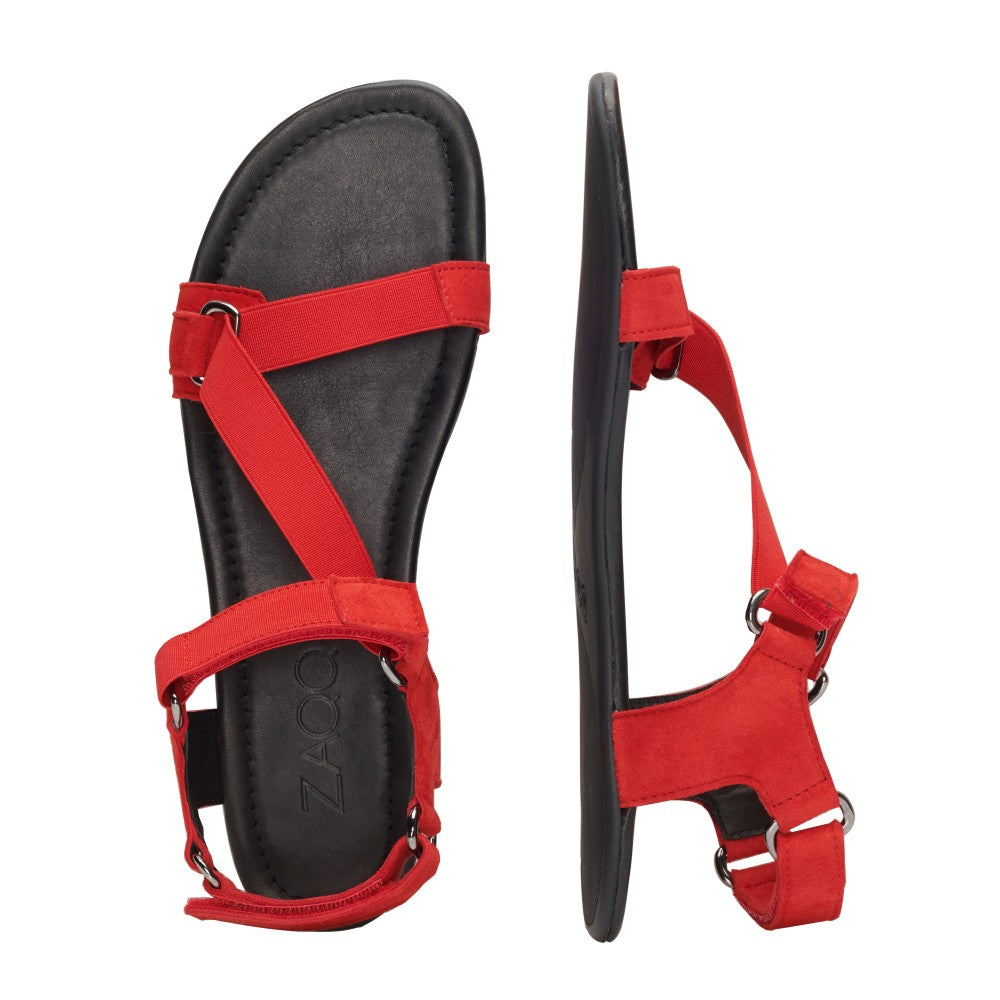 Wir präsentieren die MIQA Red von ZAQQ: Ein Paar rote Sandalen mit schwarzen Sohlen, mit Riemchensystem-Design mit sich kreuzenden Riemen und verstellbaren Verschlüssen. Im minimalistischen MIQA-Stil gefertigt, wird eine Sandale von oben und die andere von der Seite gezeigt.