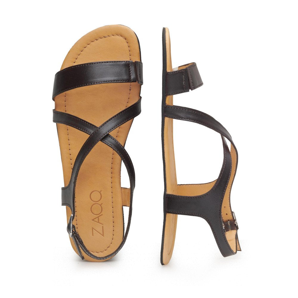 Die QEE Dark Brown Sandalen von ZAQQ zeichnen sich durch ein Design mit eleganten schwarzen Lederriemen und einer hellbraunen Kautschuksohle aus. Eine Sandale ist von oben zu sehen und zeigt ihr gekreuztes Lederriemenmuster, während die andere von der Seite präsentiert wird, um den Knöchelriemen hervorzuheben.