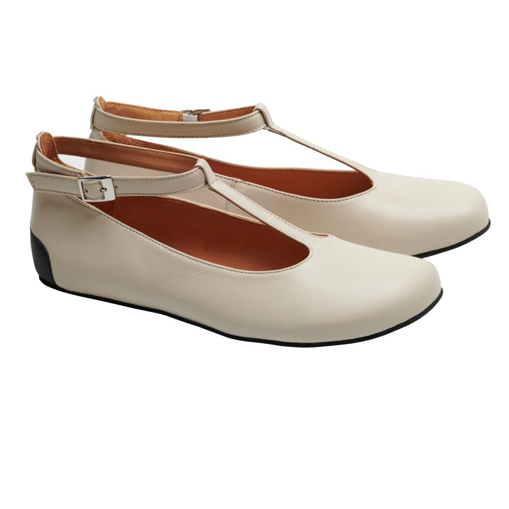 Die flachen Schuhe QITE Beige mit T-Riemen von ZAQQ haben eine seitliche Schnalle und schwarze Sohlen. Sie sind aus hochwertigem Nappaleder gefertigt und bieten ein elegantes Design und eine glatte Textur. Der Barfußschuh-Stil sorgt für Komfort und bietet eine außergewöhnliche Mischung aus Eleganz und Funktionalität.