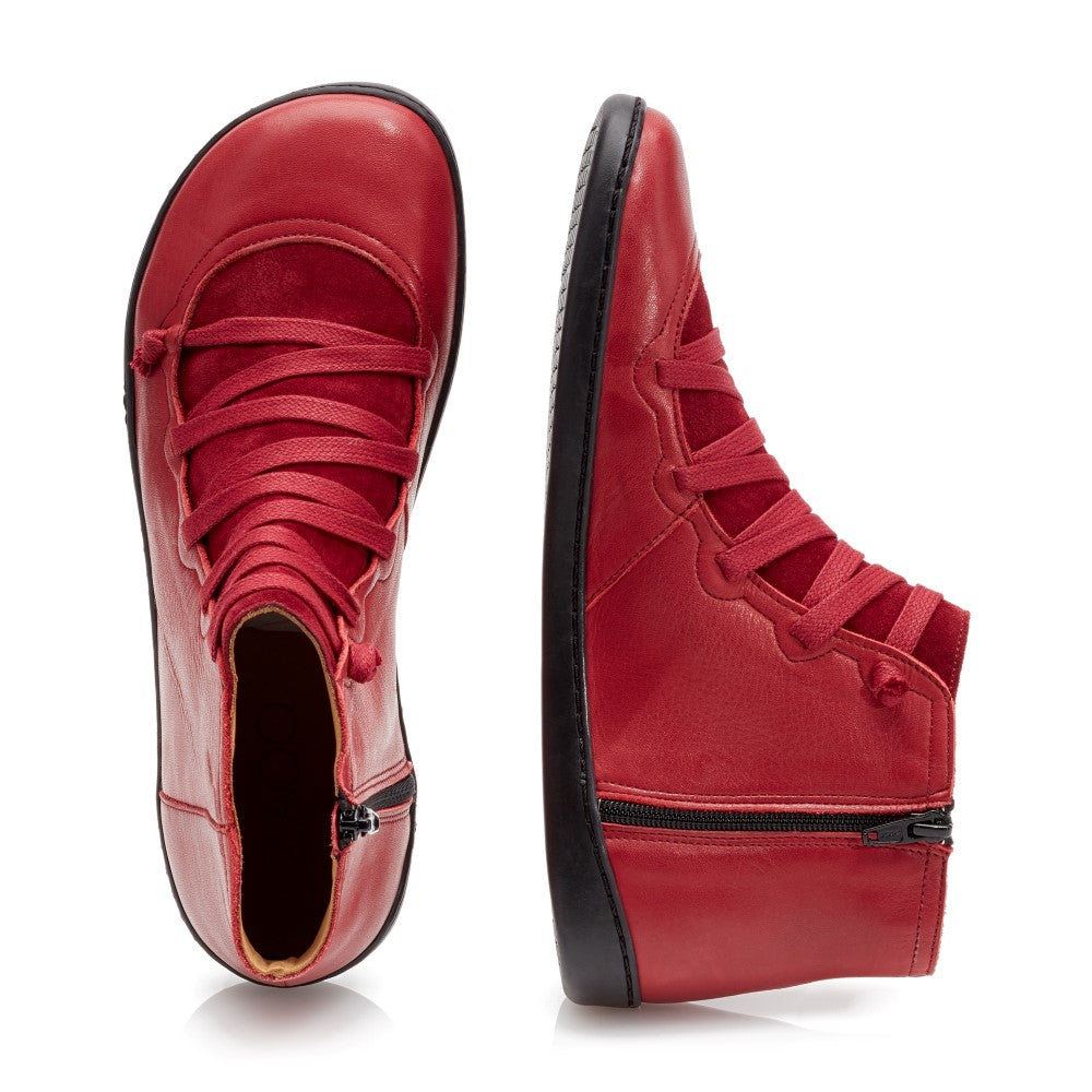 Ein Paar leuchtend rote QUECHEE Velvet High-Top-Sneaker mit schwarzer Sohle. Ein Sneaker von ZAQQ steht aufrecht und hebt seine Seite und seinen Reißverschluss hervor, während der andere flach liegt und die Draufsicht mit aufwendigen Schnürsenkeln zeigt.