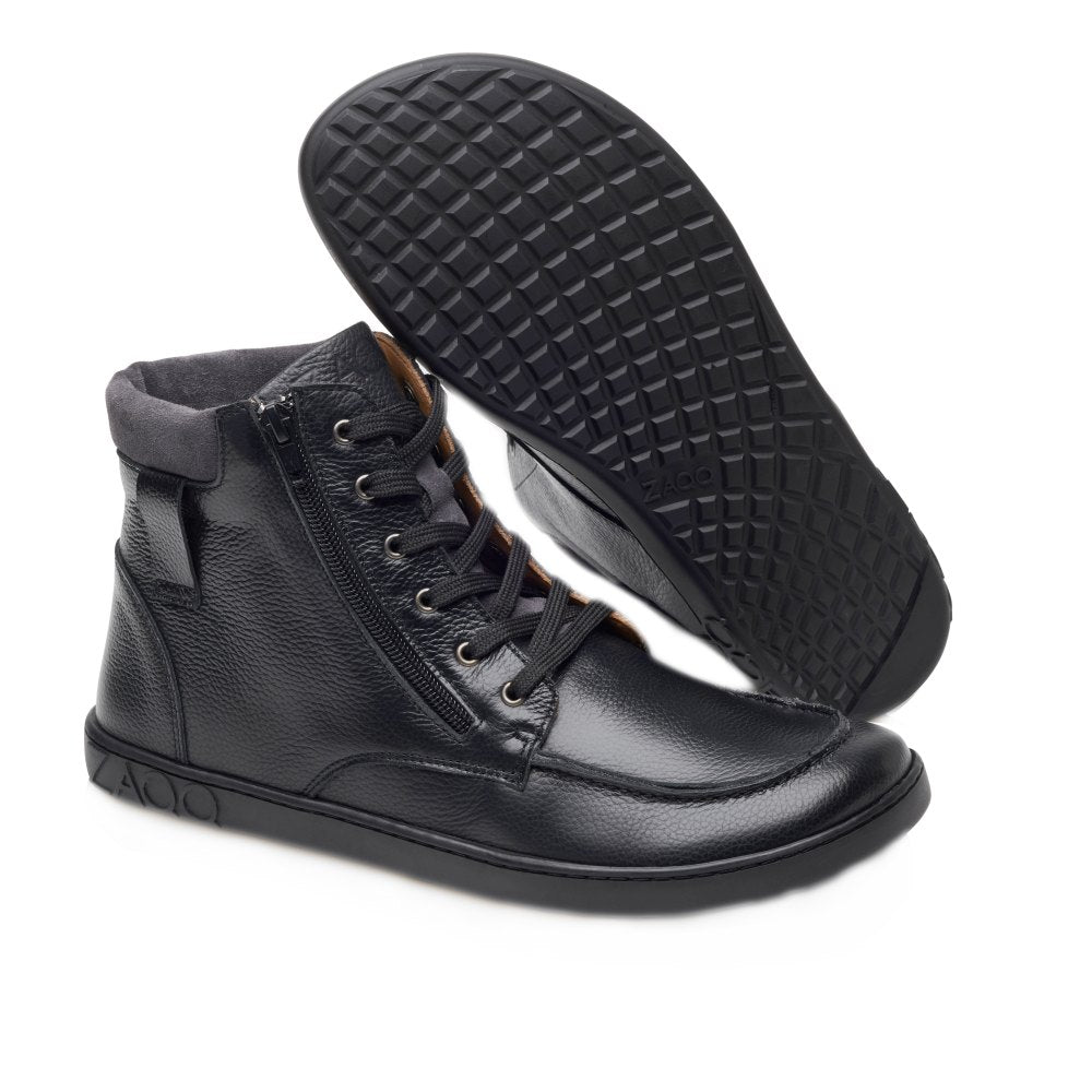 Wir präsentieren den ROQA Black von ZAQQ: ein Paar eleganter High-Top-Sneaker aus schwarzem Leder mit eleganten seitlichen Reißverschlüssen und klassischer Schnürung vorne. Der linke Schuh steht aufrecht und betont sein stilvolles Äußeres und den Reißverschluss, während der rechte Schuh auf der Seite liegt und die aufwendig strukturierte Sohle zur Schau stellt.