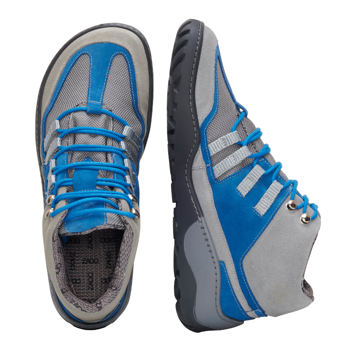 Ein Paar wasserdichte Schuhe ZAQQ ESQAPE Grey Blue in einer auffälligen Kombination aus Blau und Grau. Ein Schuh steht hoch und zeigt seine Seitenansicht, während der andere flach auf seiner Sohle liegt und der obere Teil sichtbar ist. Diese Schuhe zeichnen sich durch eine atmungsaktive Netzstruktur und leuchtend blaue Schnürsenkel aus und verbinden Stil und Funktionalität perfekt für abenteuerliche Reisen.