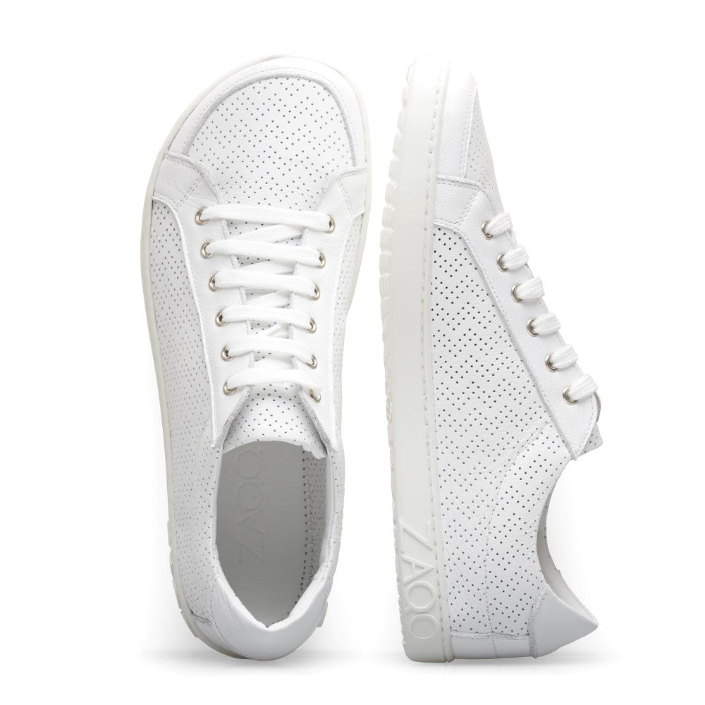 Die SLOQ White Sneaker von ZAQQ sind aus weißem Nappaleder gefertigt und verfügen über perforierte Details an den Seiten und der Spitze. Ein Schuh wird aufrecht präsentiert und zeigt die Seite, während der andere hingelegt ist und die Draufsicht zeigt. Sie werden mit weißen Schnürsenkeln und einer strukturierten, flexiblen Kautschuksohle geliefert.